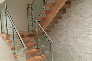 Imagen de escalera en U moderna de tamaño medio sin contrahuella con escalones de madera y barandilla de vidrio