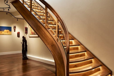 Imagen de escalera curva ecléctica grande con escalones de madera, contrahuellas de madera y barandilla de madera