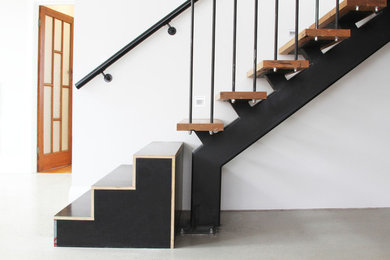Cette image montre un escalier design en U avec des marches en bois et un garde-corps en métal.