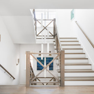 Beach style wood u-shaped staircase in Los Angeles with painted wood risers and cable railing.