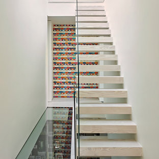 This is an example of a modern wood straight glass railing staircase in London with open risers.