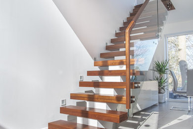 Diseño de escalera recta contemporánea grande con escalones de madera y barandilla de vidrio