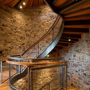 Immagine di una grande scala curva rustica con pedata in legno