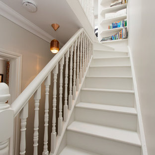 Classic painted wood straight wood railing staircase in London with painted wood risers.