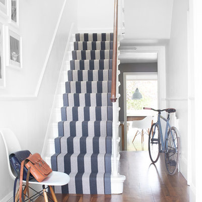 Example of a transitional painted u-shaped staircase design in London with painted risers