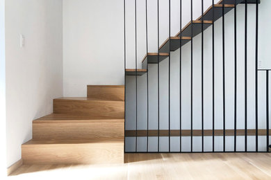 Foto de escalera en L minimalista de tamaño medio con escalones de madera, contrahuellas de metal y barandilla de metal