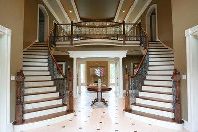 Large elegant wooden curved mixed material railing staircase photo in Chicago with painted risers