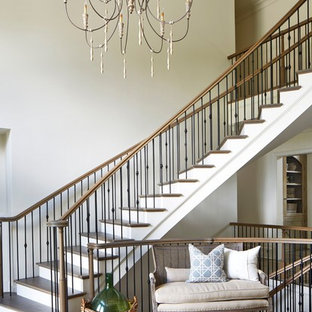 Immagine di un'ampia scala curva classica con pedata in legno e alzata in legno verniciato