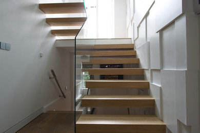 Inspiration for a medium sized contemporary wood u-shaped staircase in London with open risers.