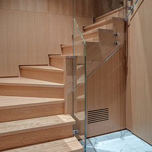 Idee per una piccola scala moderna con pedata in legno e parapetto in vetro