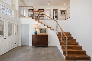 Cette image montre un grand escalier minimaliste en L avec des marches en bois, des contremarches en bois, un garde-corps en câble et éclairage.