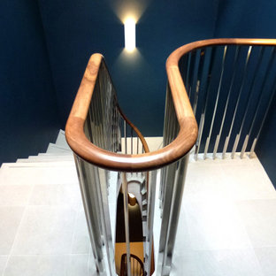 Foto di una scala curva minimal con pedata in pietra calcarea, alzata in pietra calcarea e parapetto in legno