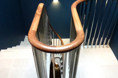 サセックスにあるコンテンポラリースタイルのおしゃれなサーキュラー階段 (ライムストーンの蹴込み板、木材の手すり) の写真