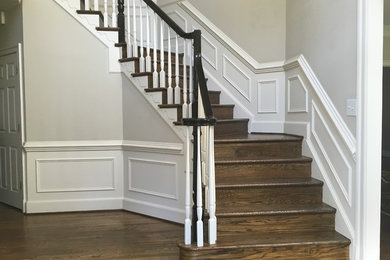 Ejemplo de escalera curva clásica renovada grande con escalones de madera, contrahuellas de madera y barandilla de madera