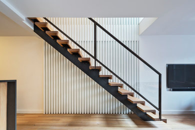 Ejemplo de escalera recta moderna de tamaño medio sin contrahuella con escalones de madera y barandilla de metal