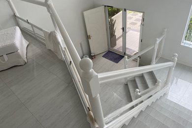 Ejemplo de escalera en U bohemia de tamaño medio con escalones con baldosas, contrahuellas con baldosas y/o azulejos y barandilla de madera