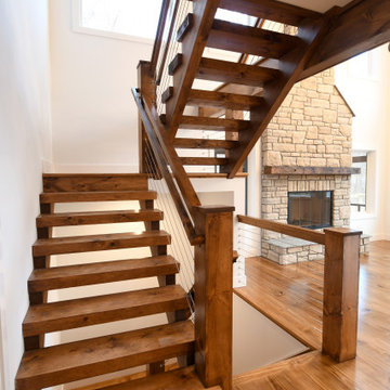 Modern country staircase features steel cable rails.