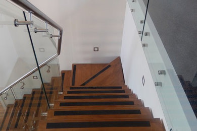 Ejemplo de escalera en L moderna pequeña sin contrahuella con escalones de madera y barandilla de vidrio