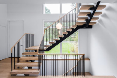 Ejemplo de escalera en U moderna grande sin contrahuella con escalones de madera y barandilla de metal