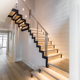 Esempio di una grande scala sospesa minimalista con pedata in legno, alzata in metallo e parapetto in metallo