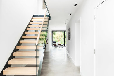 Foto de escalera recta de tamaño medio con escalones de madera, contrahuellas de madera y barandilla de vidrio