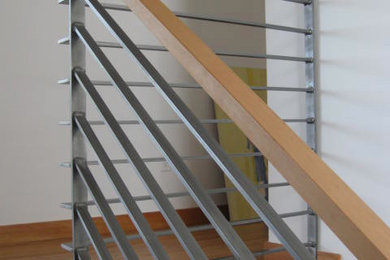 Modelo de escalera en L contemporánea de tamaño medio con escalones de madera, contrahuellas de madera y barandilla de metal