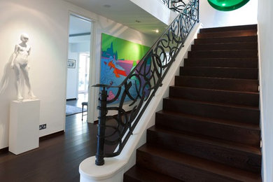 Cette image montre un escalier minimaliste avec des marches en bois, des contremarches en bois et un garde-corps en métal.