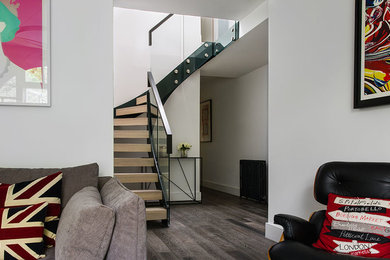This is an example of a medium sized contemporary wood l-shaped glass railing staircase in West Midlands with open risers.