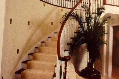 На фото: большая изогнутая лестница с ступенями с ковровым покрытием и ковровыми подступенками