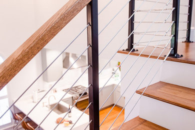 Foto de escalera recta actual de tamaño medio con escalones de madera, contrahuellas de madera pintada y barandilla de cable