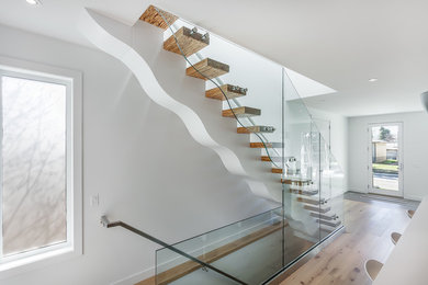 Foto de escalera recta actual grande sin contrahuella con escalones de madera y barandilla de vidrio
