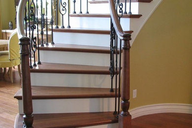 Example of a classic wooden curved staircase design in Los Angeles with painted risers