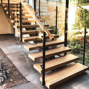 Ispirazione per una grande scala a rampa dritta design con pedata in legno, alzata in vetro e parapetto in materiali misti