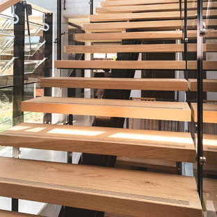 Idee per una grande scala a rampa dritta design con pedata in legno, alzata in vetro e parapetto in materiali misti