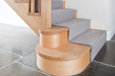 Aménagement d'un grand escalier courbe moderne avec des marches en bois, des contremarches en bois et un garde-corps en bois.