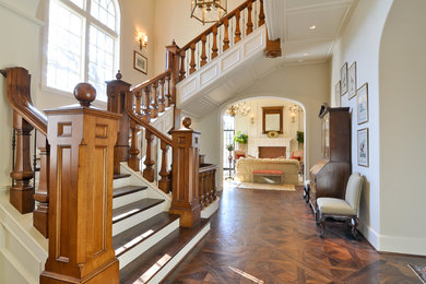 Ejemplo de escalera en L clásica extra grande con escalones de madera, contrahuellas de madera pintada y barandilla de madera