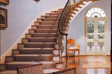 Imagen de escalera curva clásica de tamaño medio con escalones enmoquetados, contrahuellas de madera y barandilla de madera