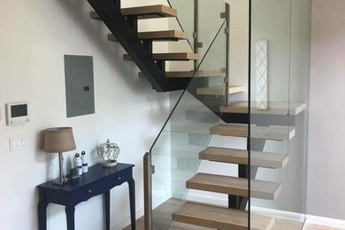 Diseño de escalera en U contemporánea de tamaño medio sin contrahuella con escalones de madera y barandilla de vidrio