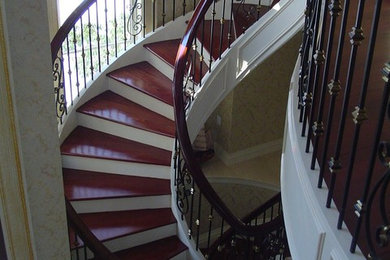 Foto de escalera curva clásica grande con escalones de madera, contrahuellas de madera pintada y barandilla de varios materiales