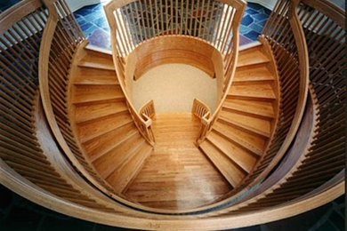 Ejemplo de escalera curva extra grande con escalones de madera y contrahuellas de madera