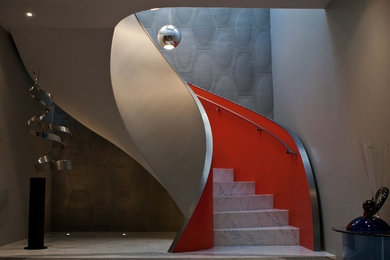 サンフランシスコにあるラグジュアリーな広いエクレクティックスタイルのおしゃれなサーキュラー階段 (大理石の蹴込み板、金属の手すり) の写真