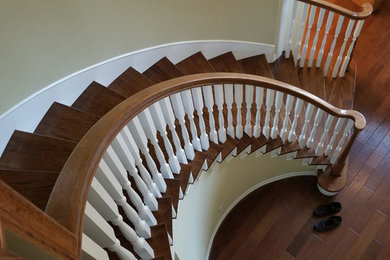Ejemplo de escalera curva clásica de tamaño medio con escalones de madera, contrahuellas de madera y barandilla de madera