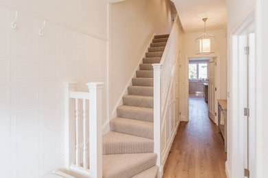 Photo of a small traditional l-shaped wood railing staircase in London with wood risers.