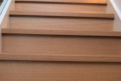 Foto de escalera recta moderna con escalones de madera, contrahuellas de madera y barandilla de vidrio