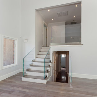 Example of a mid-sized minimalist wooden straight glass railing staircase design in Los Angeles with painted risers
