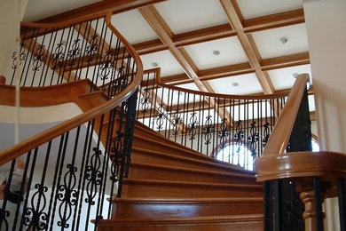 На фото: большая изогнутая деревянная лестница с металлическими ступенями с