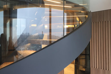 Inspiration for a large contemporary wood curved glass railing staircase in Sydney with open risers.