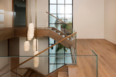 Foto de escalera en U minimalista grande sin contrahuella con escalones de madera y barandilla de vidrio