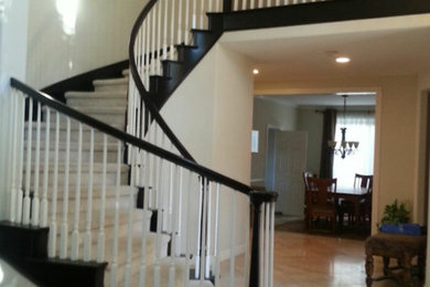 На фото: изогнутая лестница среднего размера в стиле неоклассика (современная классика) с ступенями с ковровым покрытием, ковровыми подступенками и деревянными перилами с