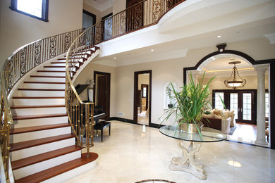 Diseño de escalera curva clásica grande con escalones de madera, contrahuellas de madera pintada y barandilla de metal